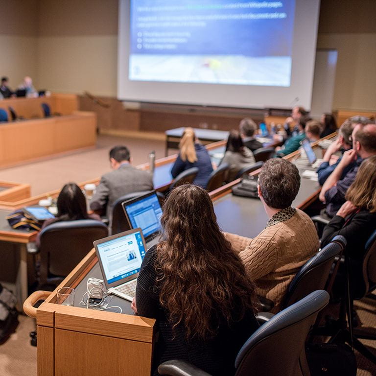 People sitting in room viewing PowerPoint presentation at 2019 Symposium.