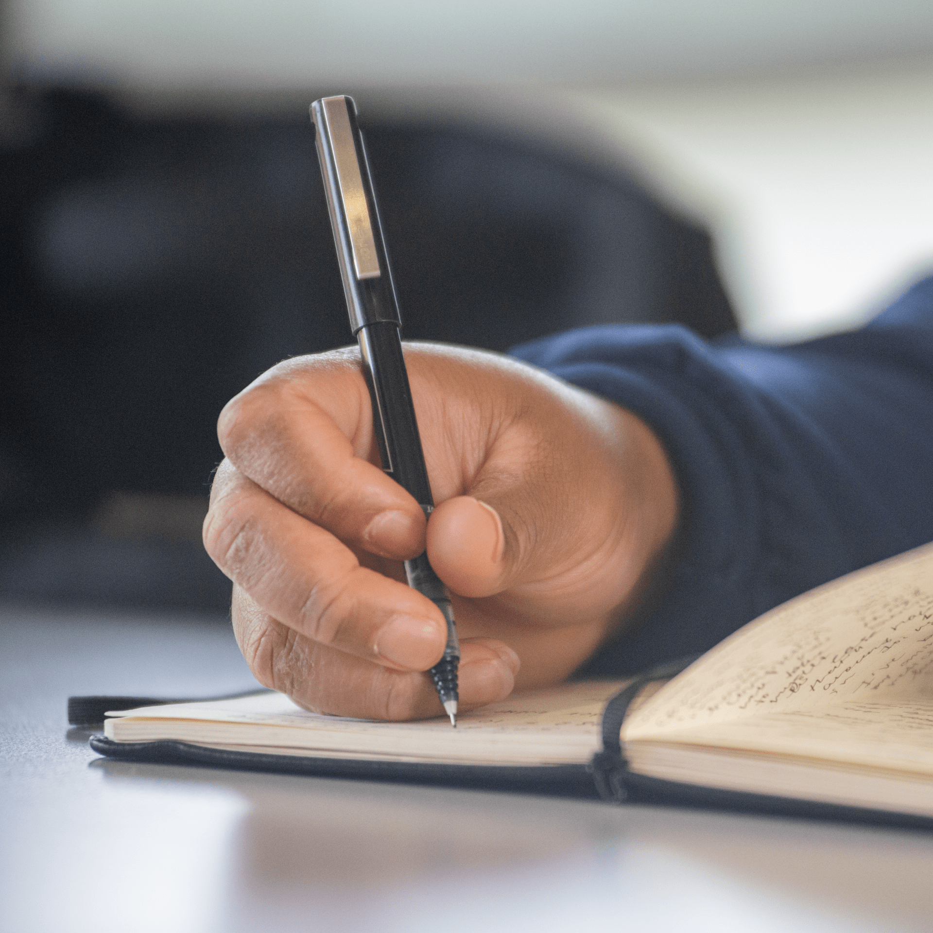 Closeup of a person writing in a journal.