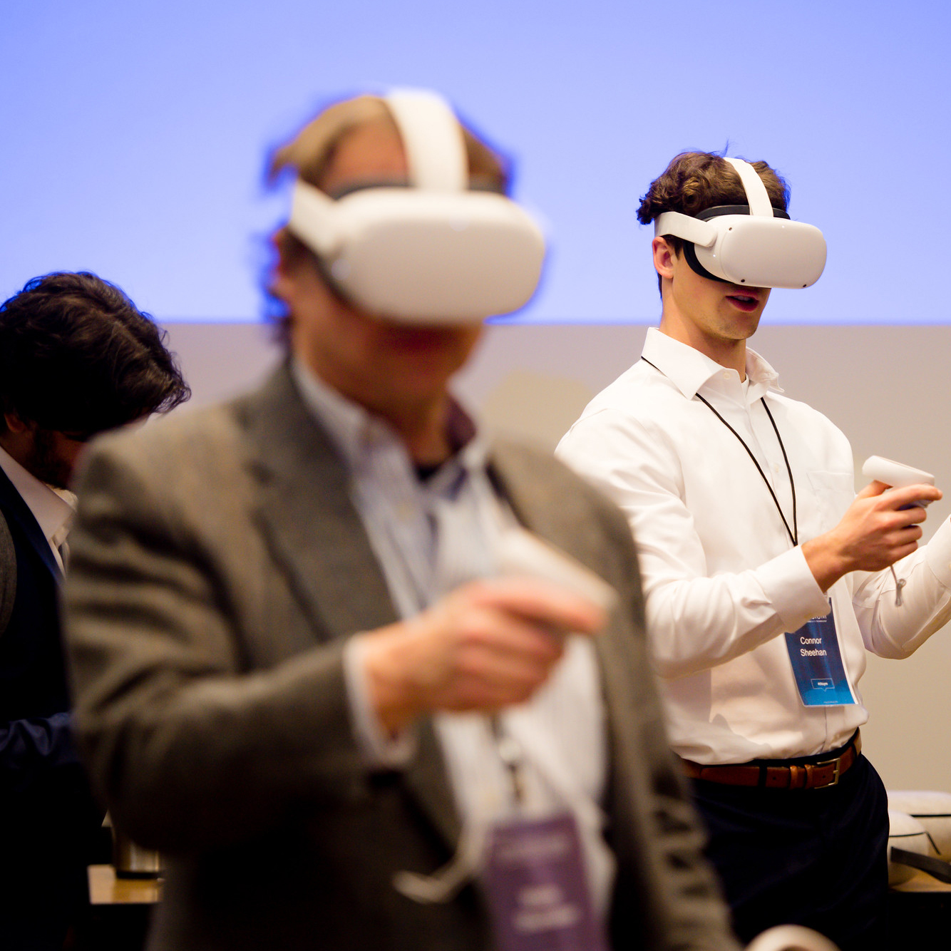 Two men interact with VR headsets at a conference